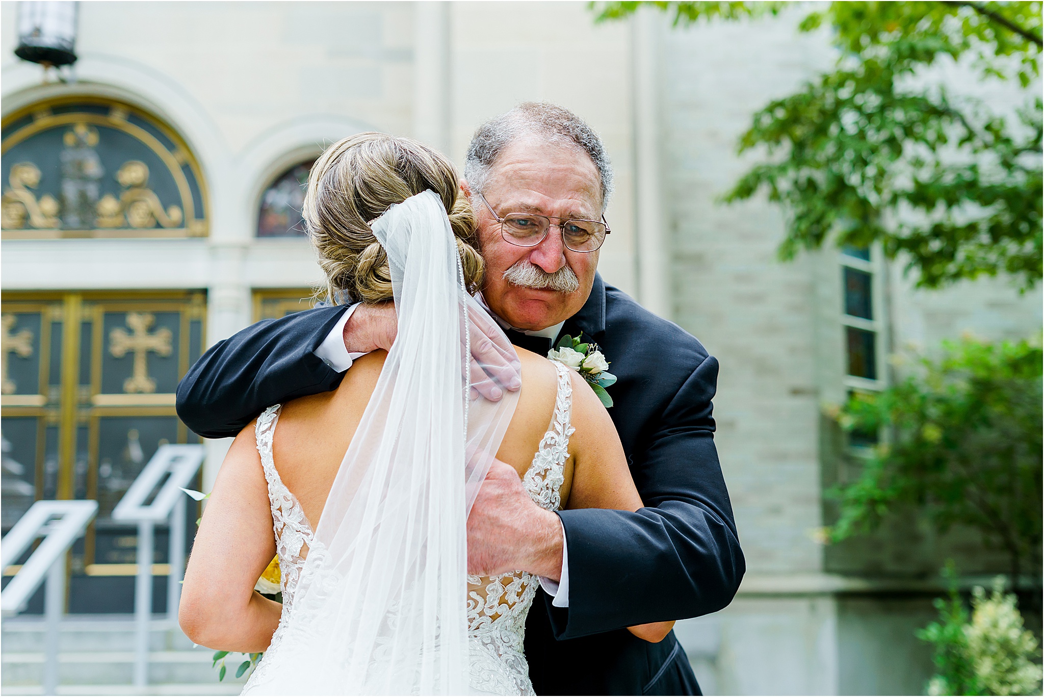 The bride's father embraces her in a hug while tearing up during their father daughter first look.