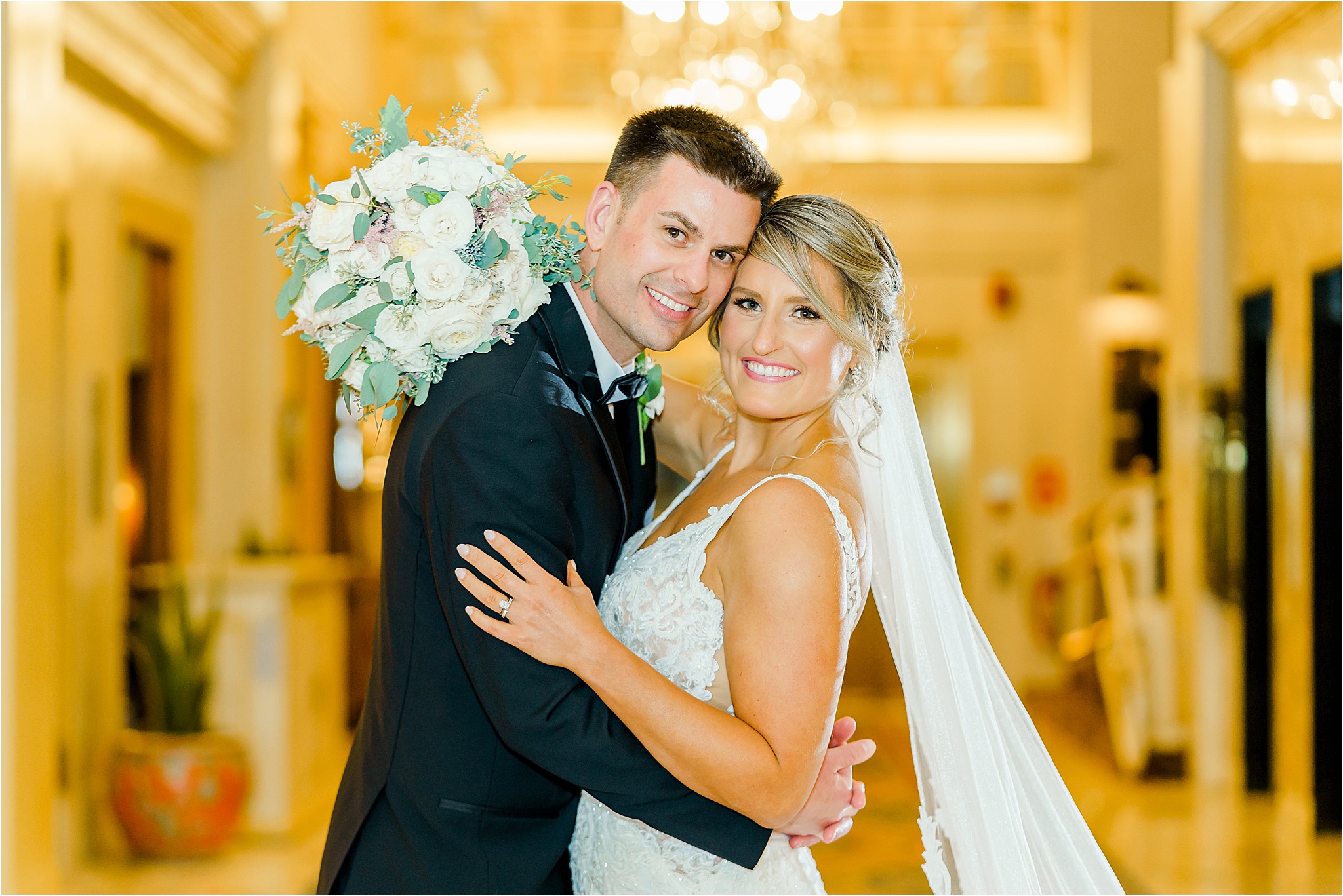 The couple holding each other with their heads together, smiling at the camera for a portrait. 