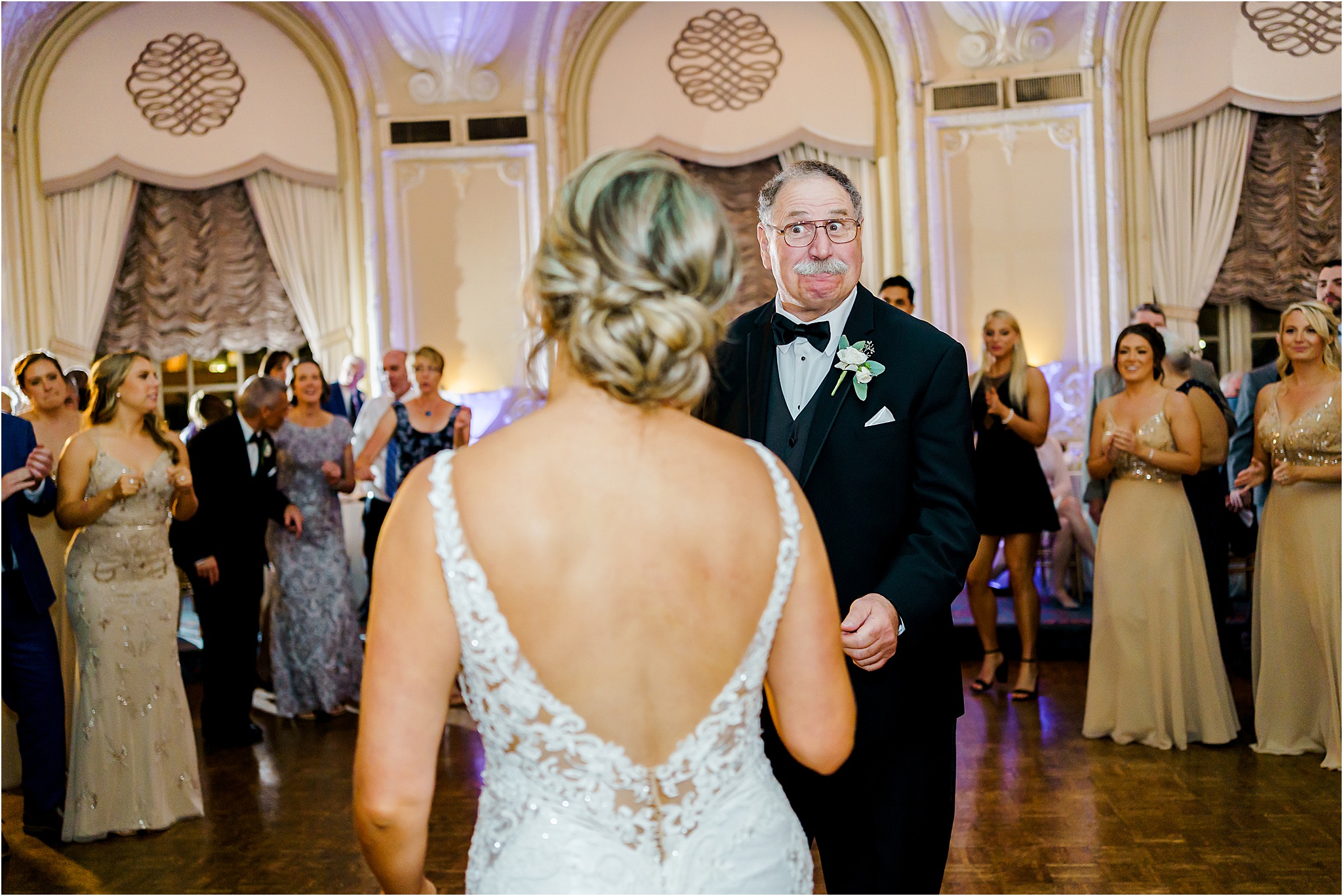 The bride's father making a funny face while dancing facing the bride.