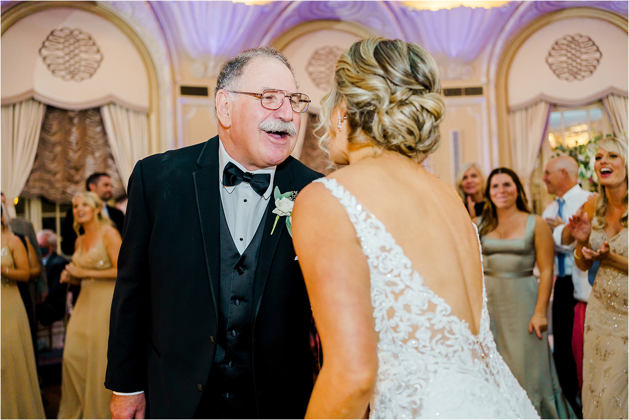 The bride's father leaning in towards the bride while singing during the reception.